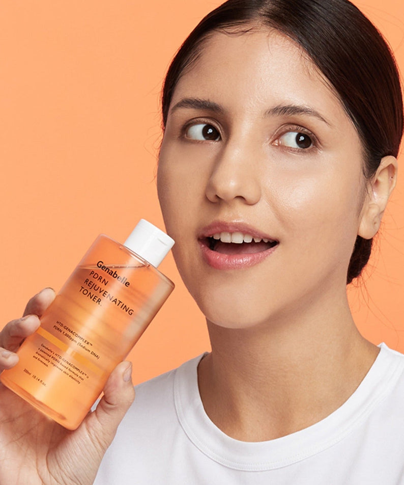 Woman holding GENABELLE PDRN Rejuvenating Toner 300ml against an orange background.