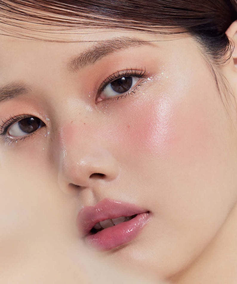 Model wearing makeup with glowing skin effect from GLINT Stick Highlighter