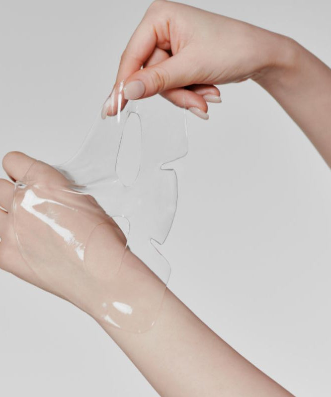 Hands holding a transparent sheet from GLOW Aloe Hydrogel Mask Pack 3ea
