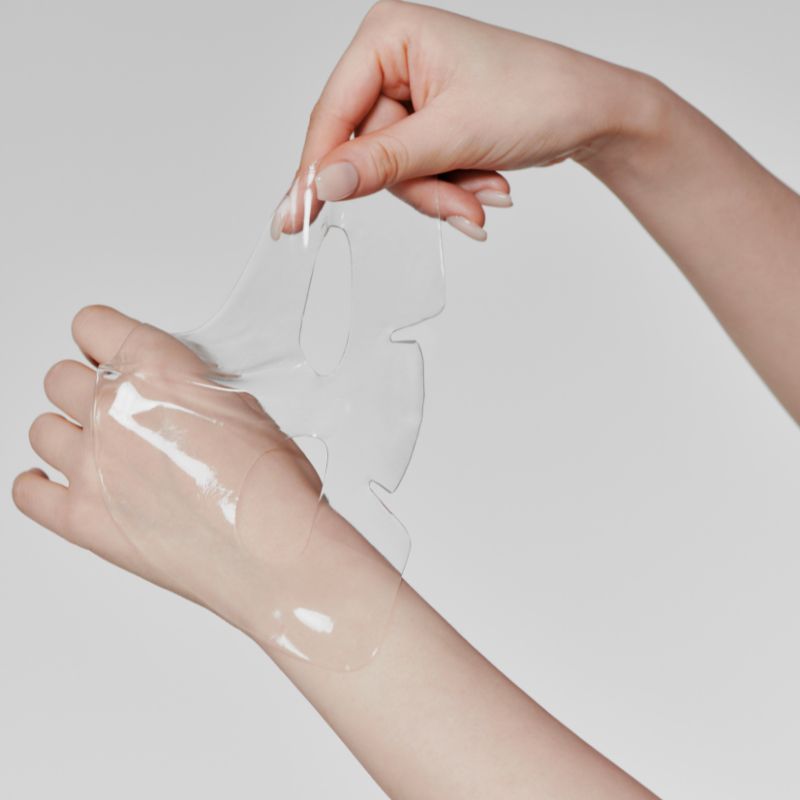 Hands holding a transparent sheet from GLOW Aloe Hydrogel Mask Pack 3ea