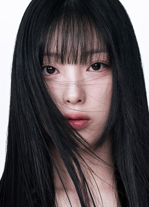 Close-up of a woman with long, straight black hair and bangs, looking directly at the camera.