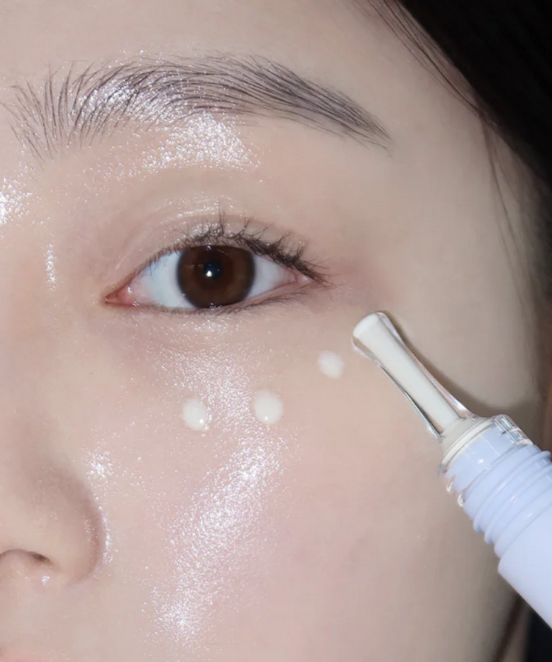 Close-up application of GLOW Apple Retinol Eye Cream 15ml on woman's under-eye area.