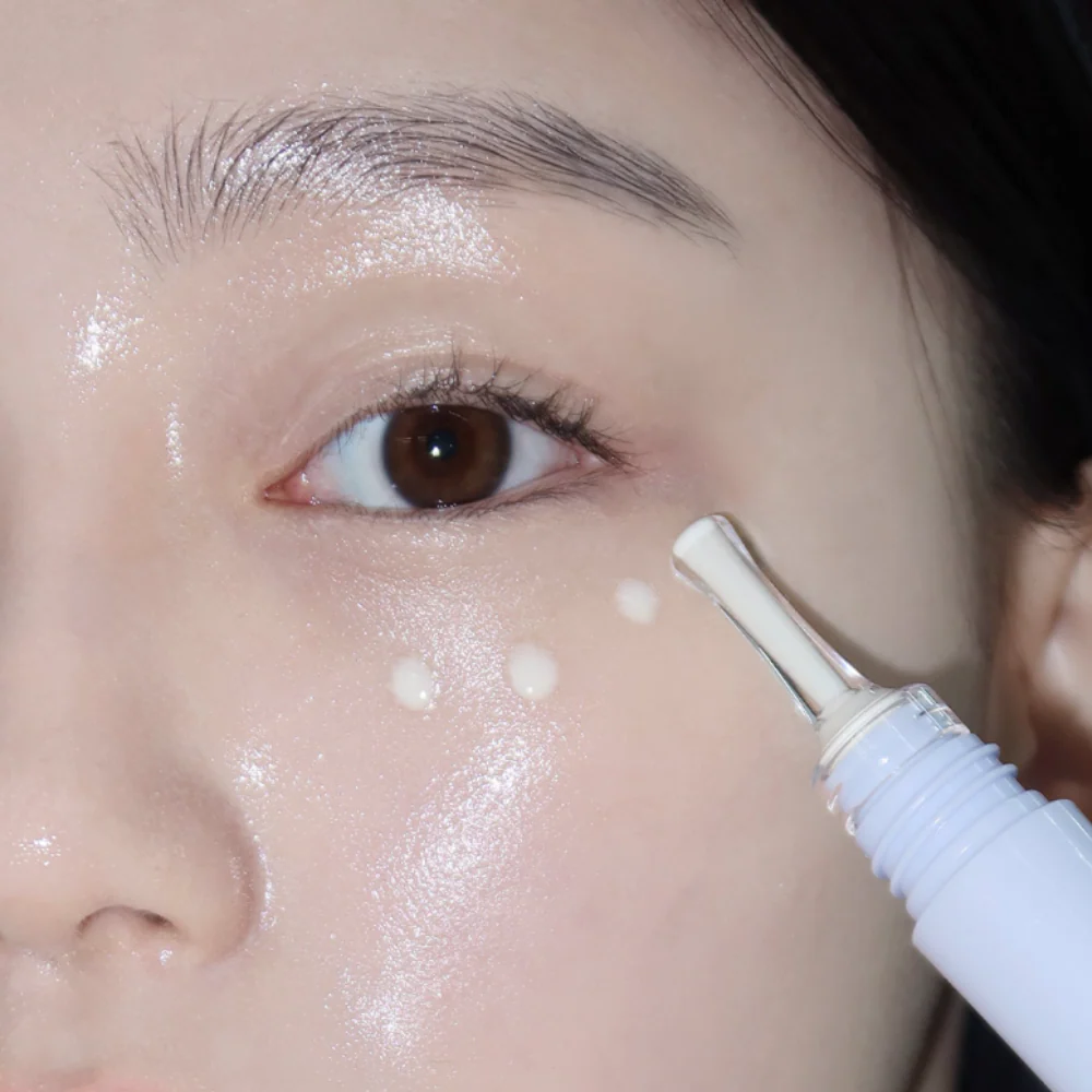 Close-up application of GLOW Apple Retinol Eye Cream 15ml on woman's under-eye area.