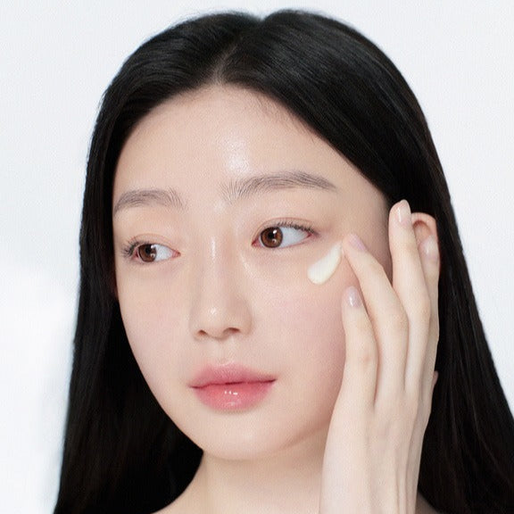 Woman applying GLOW Apple Retinol Eye Cream 15ml under her eye for smooth and hydrated skin.