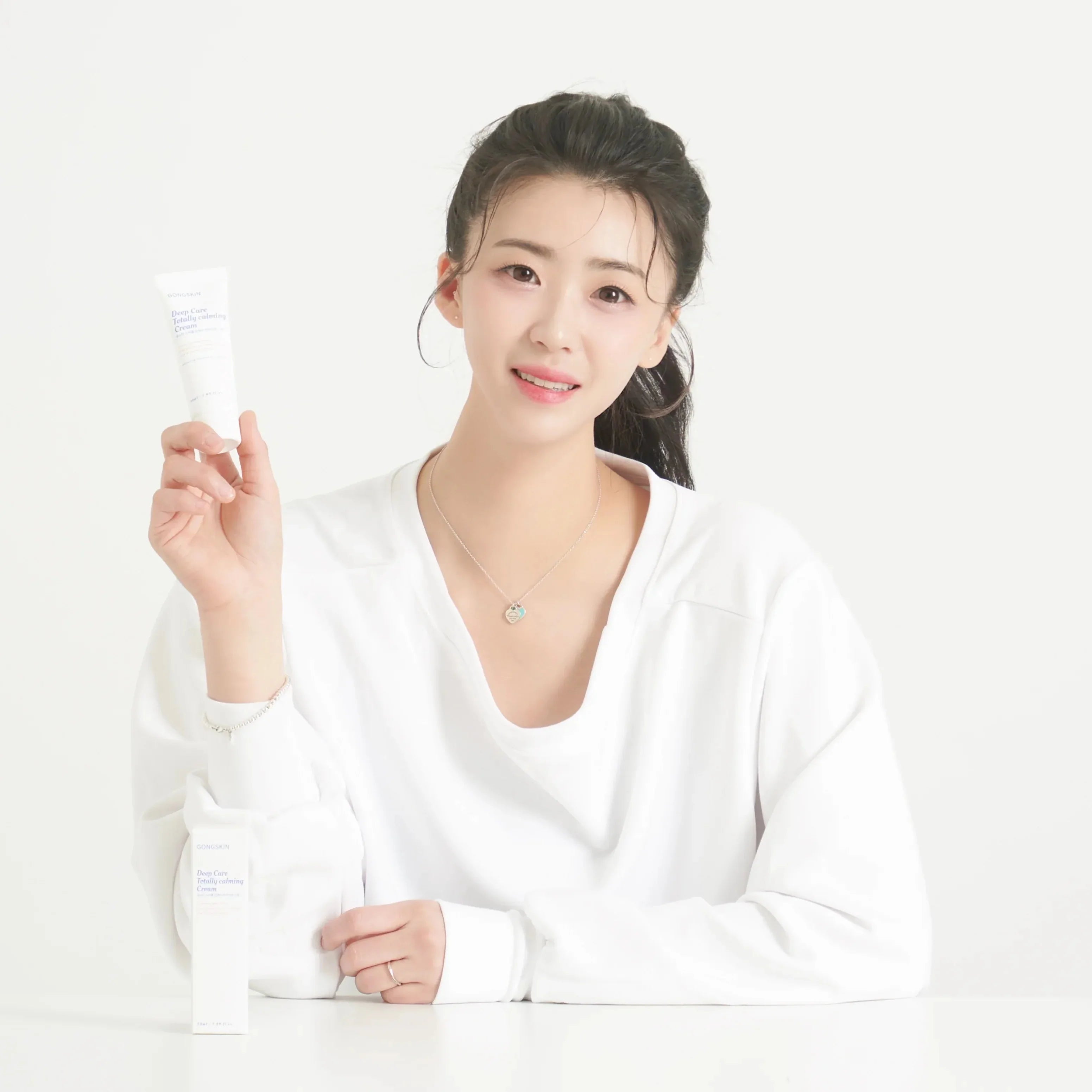 Woman holding GONGKIN Deep Care Totally calming Cream 50ml, skincare product.