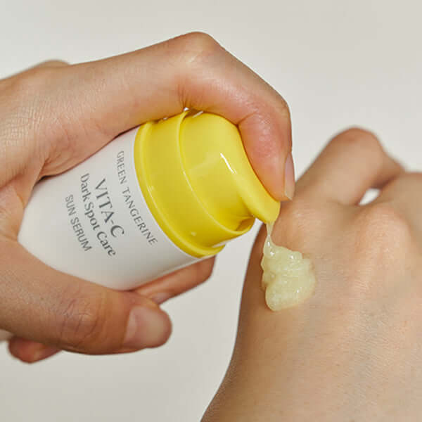 GOODAL Green Tangerine Vita C Spot Care Sun Serum 50ml being applied to skin from pump bottle, demonstrating texture and color.