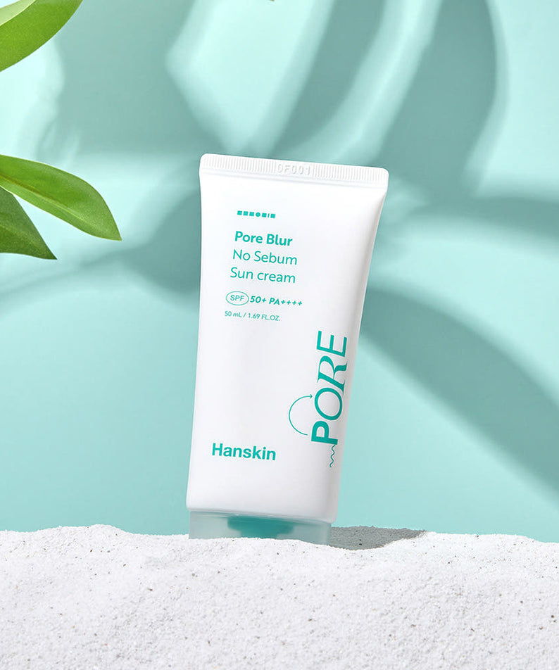 HANSKIN Pore Blur No-Sebum Sunscreen SPF50+ PA++++ 50ml product image on a sandy beach with green leaves.