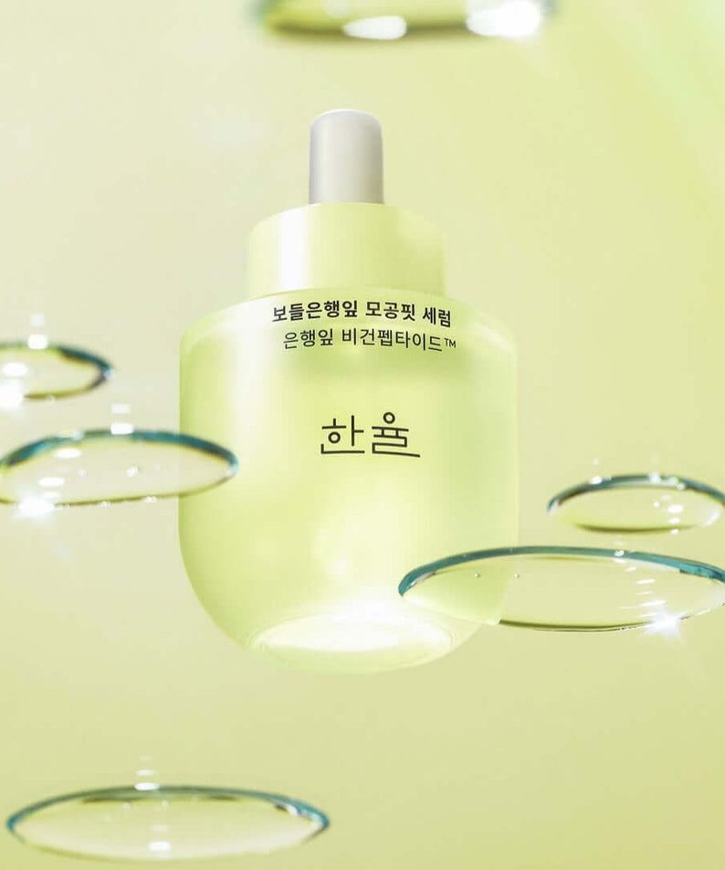 HANYUL Bodunhaengip Pore Fir Serum bottle with fresh glistening droplets on a light green background, showcasing skincare product elegance.