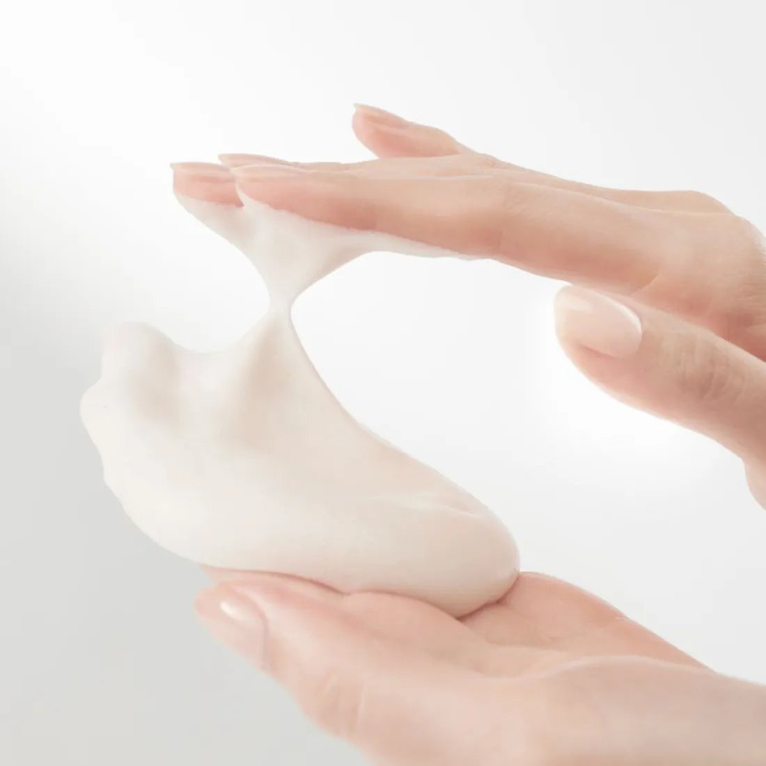 HANYUL Extreme Cream Cleansing Foam 200ml being applied with hands, showcasing its creamy texture.
