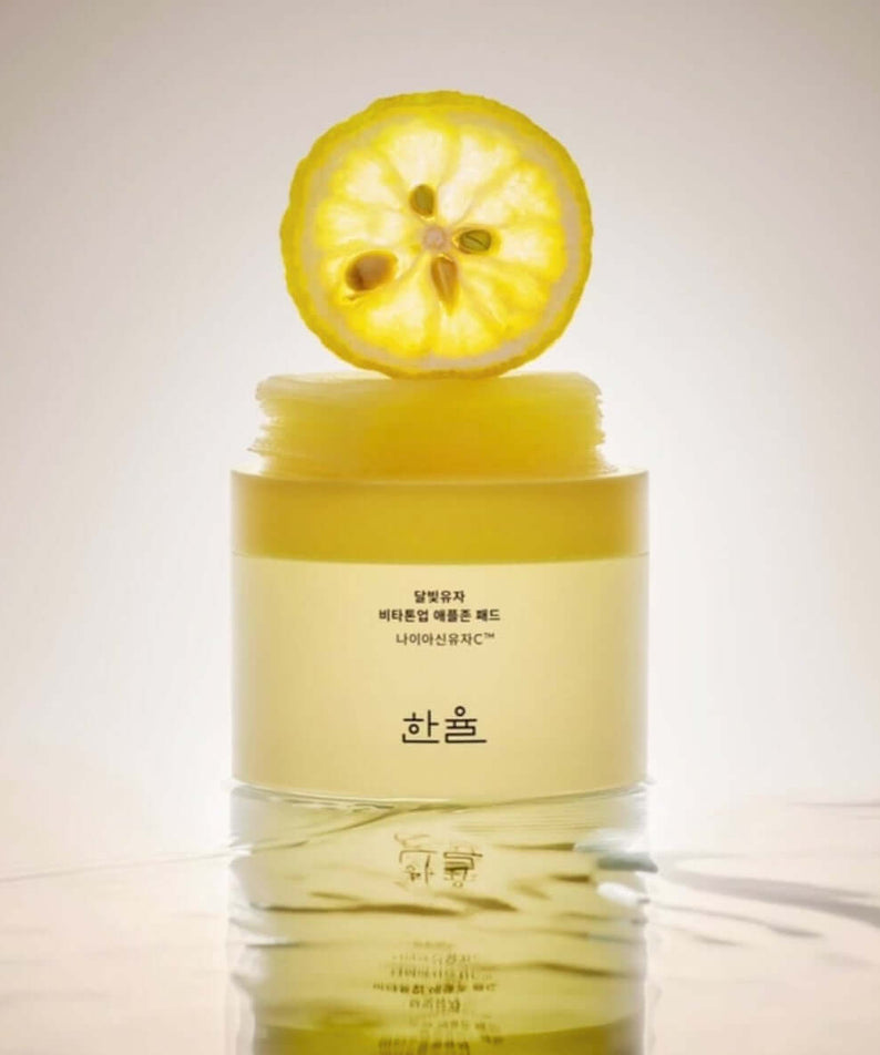 HANYUL Moonlight Yuja Vita Tone Up Apple Zone Pad with a citrus slice on top, enhancing natural skin glow and luminosity.