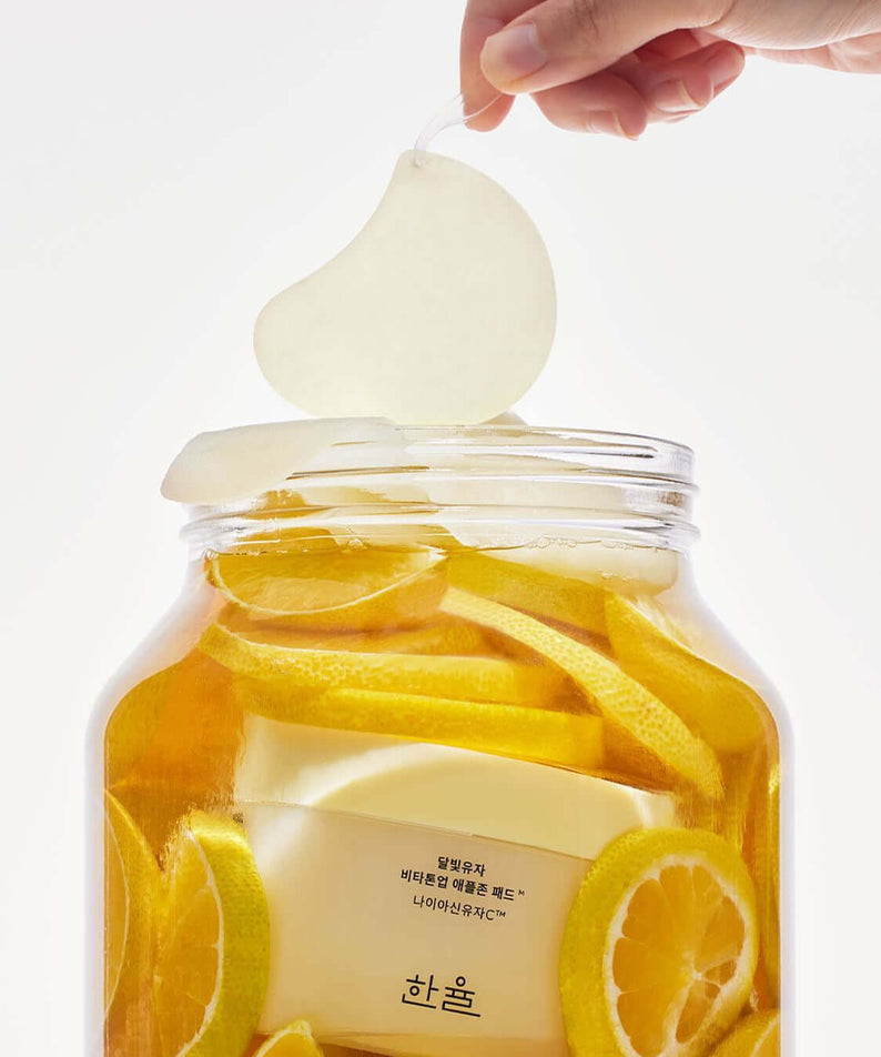 HANYUL Moonlight Yuja Vita Tone Up Apple Zone Pad with citrus slices in a jar, enhancing skin tone and radiance.