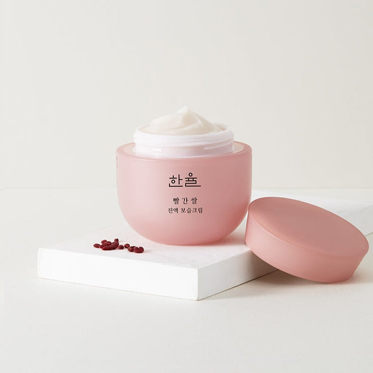 HANYUL Red Rice Essential Moisture Cream 50ml jar stylishly displayed with open lid on white platform