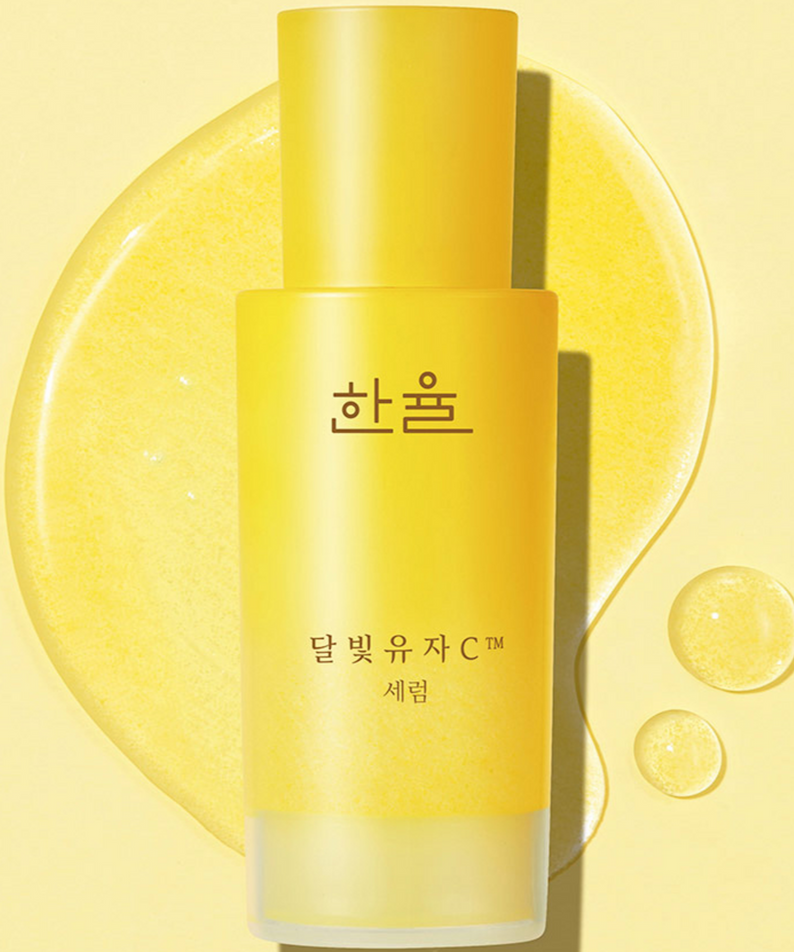 HANYUL Yuja Vitamin C Brightening Serum 50ml in a yellow bottle with liquid highlights on a bright yellow background.