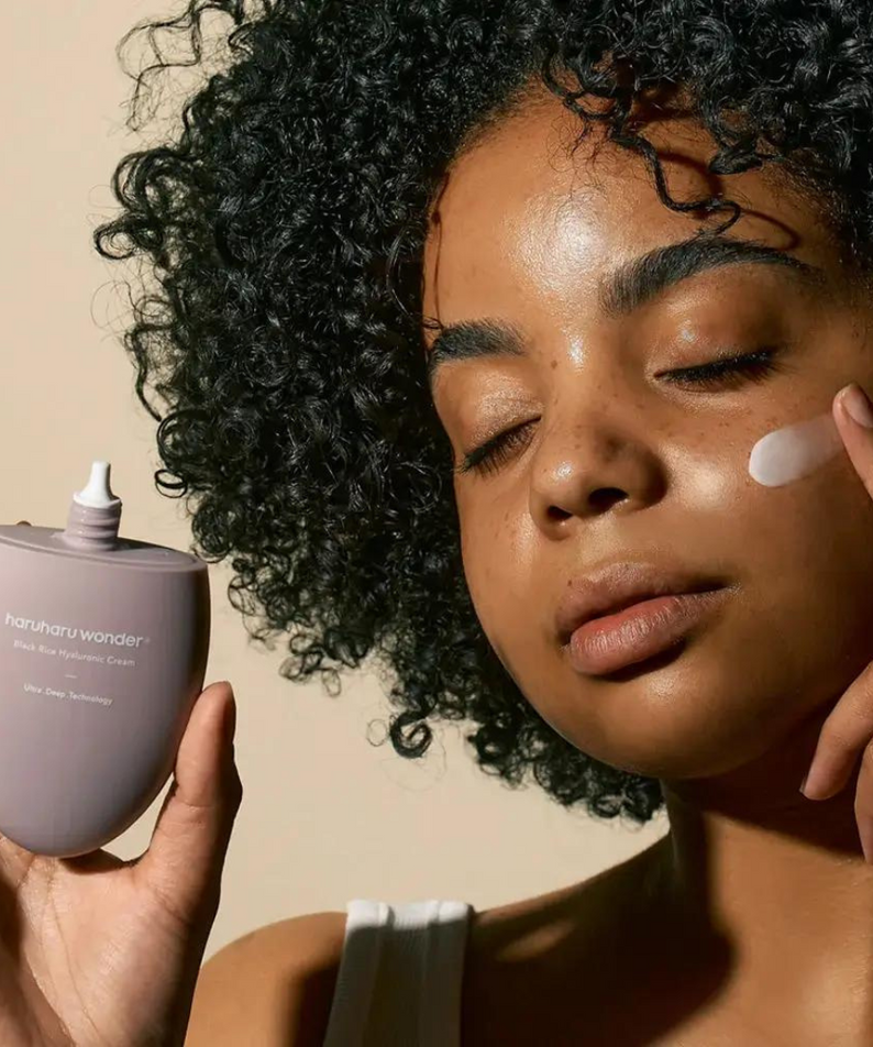 Woman applying HARUHARU Black Rice 10 Hyaluronic Cream 50ml to her face, showcasing skincare routine with product in hand