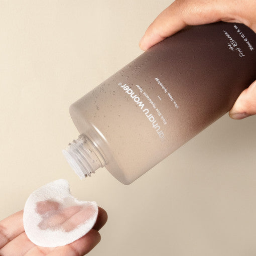 HARUHARU Black Rice Hyaluronic Toner being poured onto a cotton pad from a bottle, highlighting skin hydration properties.