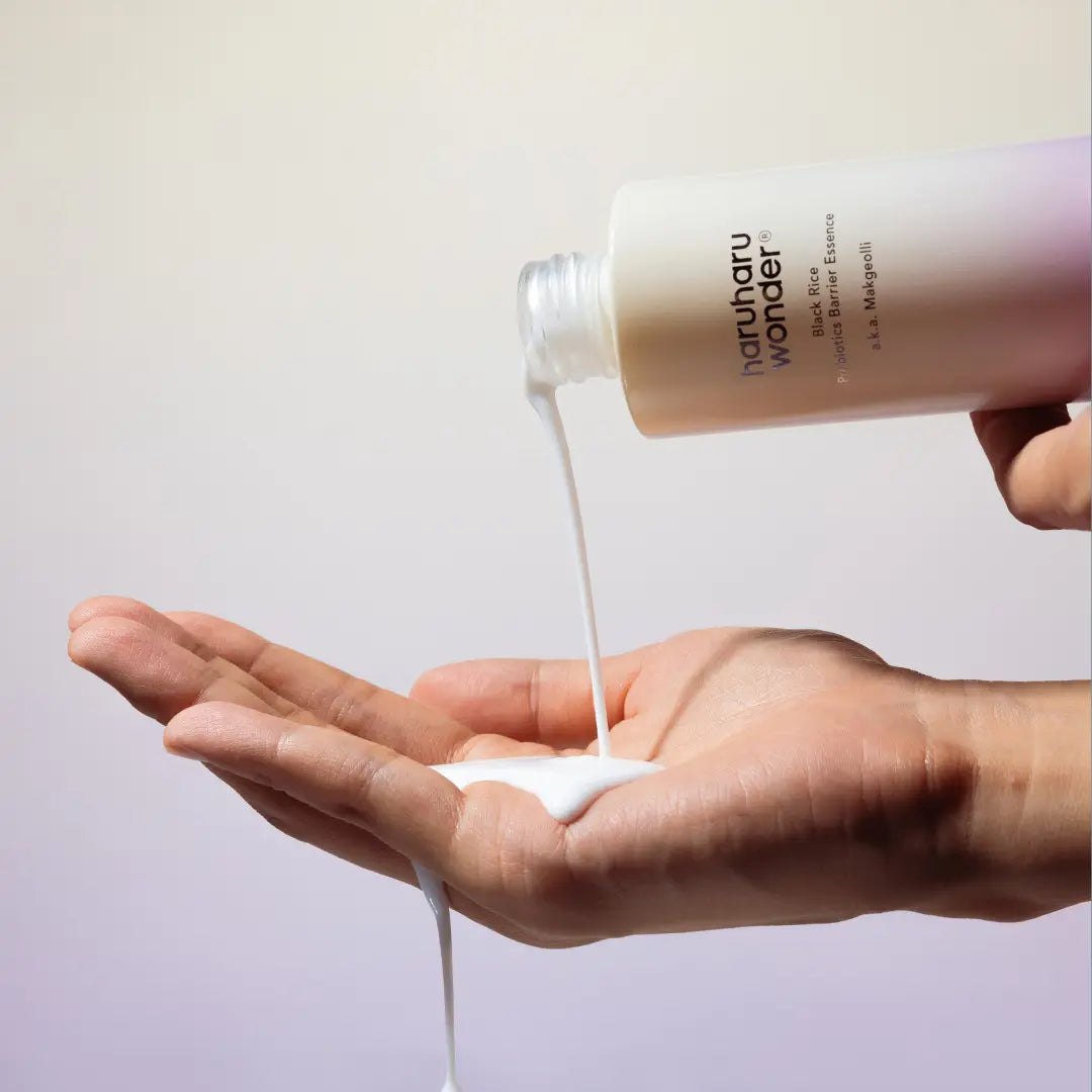 HARUHARU Black Rice Probiotics Barrier Essence 120ml being poured onto a hand, showcasing the product's texture and application.
