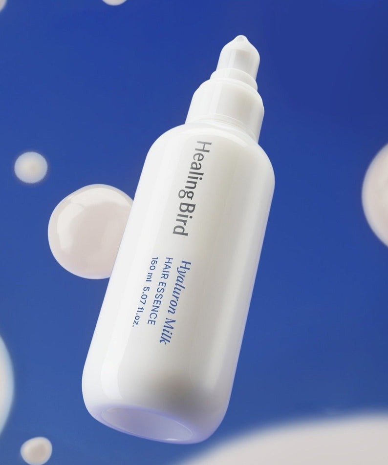 HEALING BIRD Hyaluronic Milk Hair Essence 150ml bottle image against a blue background with bubbles.
