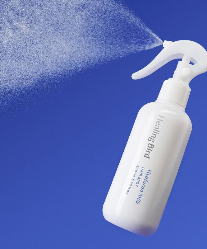 HEALING BIRD Hyalutonic Milk Hair Mist 200ml in white spray bottle against blue background.