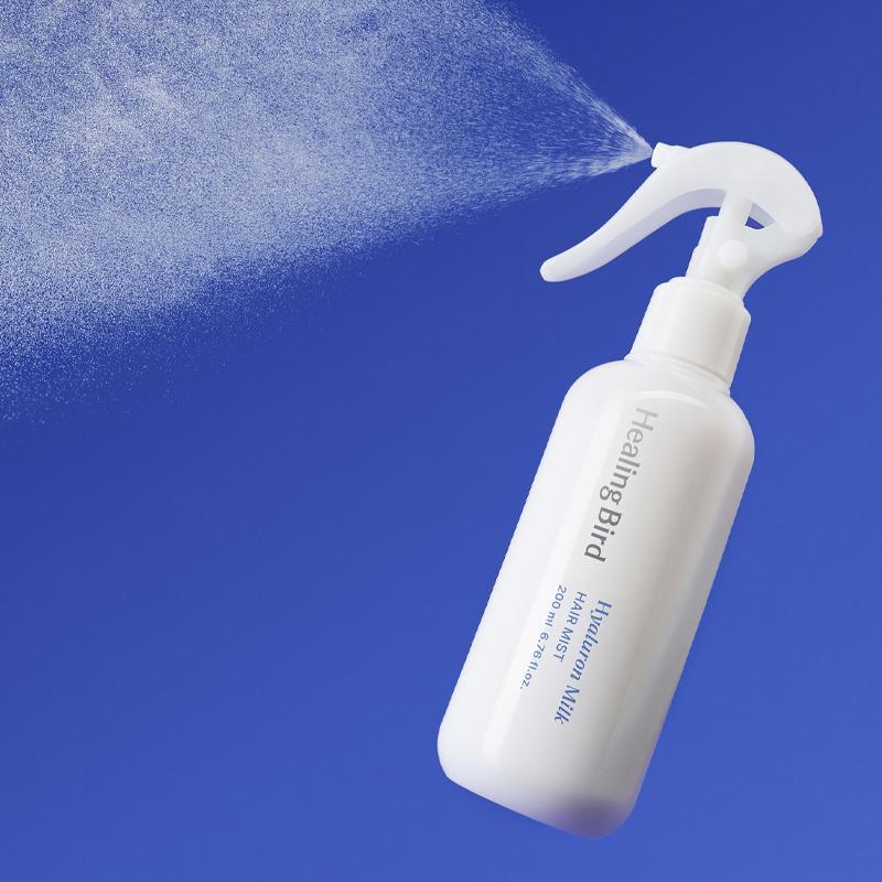 HEALING BIRD Hyalutonic Milk Hair Mist 200ml in white spray bottle against blue background.