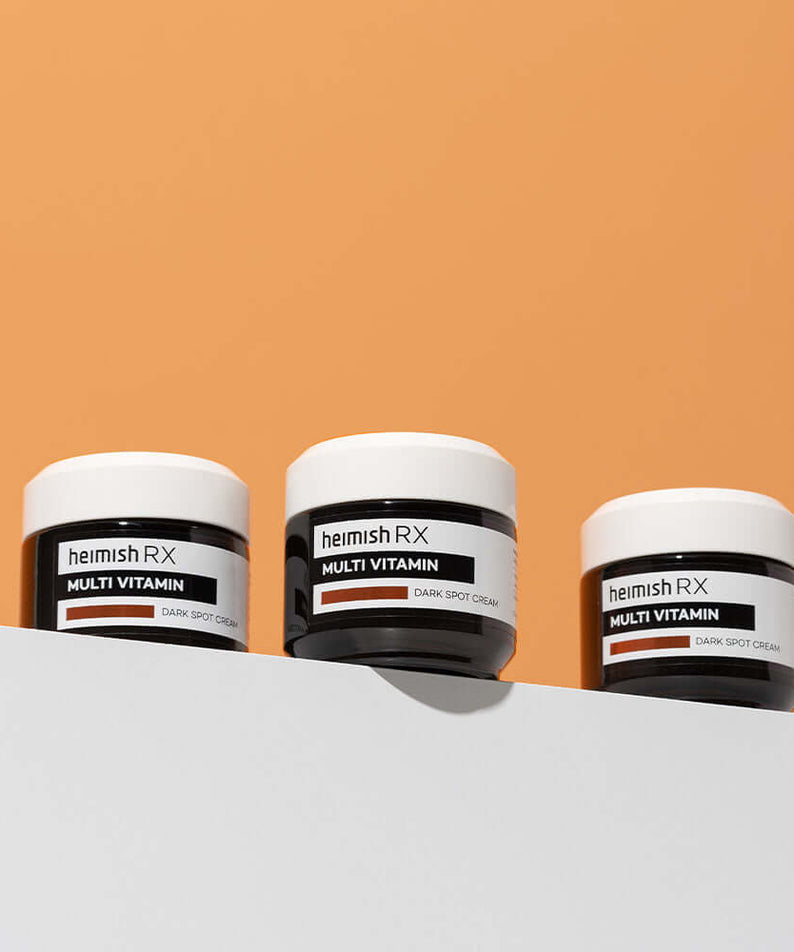 HEIMISH RX Multi Vitamin Dark Spot Cream 50ml on display against orange background.