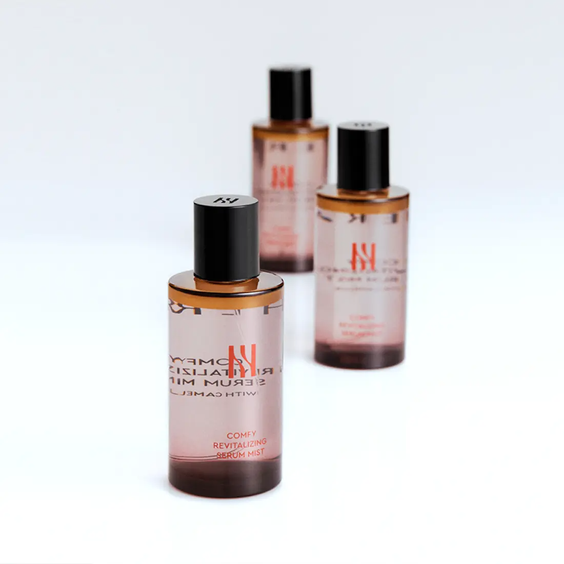 Three bottles of HERA Comfy Revitalizing Serum Mist 90ml on a white background.