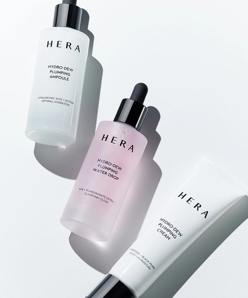 HERA Hydro-Dew Pluming Water Drop 50ml surrounded by skincare essentials in a bright setting.