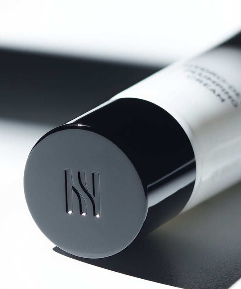 Close-up of HERA Hydro-Dew Plumping Cream 50ml cap on a white surface for skincare enthusiasts.