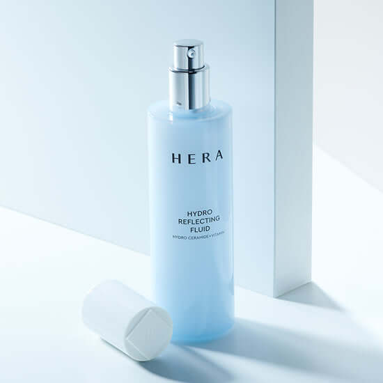 HERA Hydro Reflecting Fluid 140ml bottle with cap placed beside it, showcasing the sleek design and packaging.