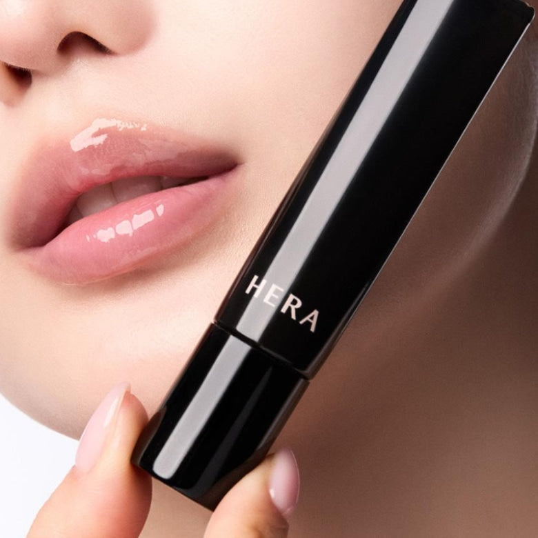 Close-up of a model applying HERA Lip Serum Intense 11g for a glossy finish.