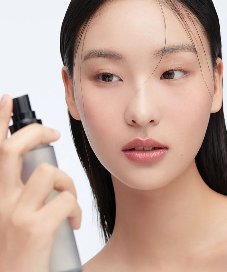 Woman using HERA Make Up Fixer 80ml for a flawless finish.