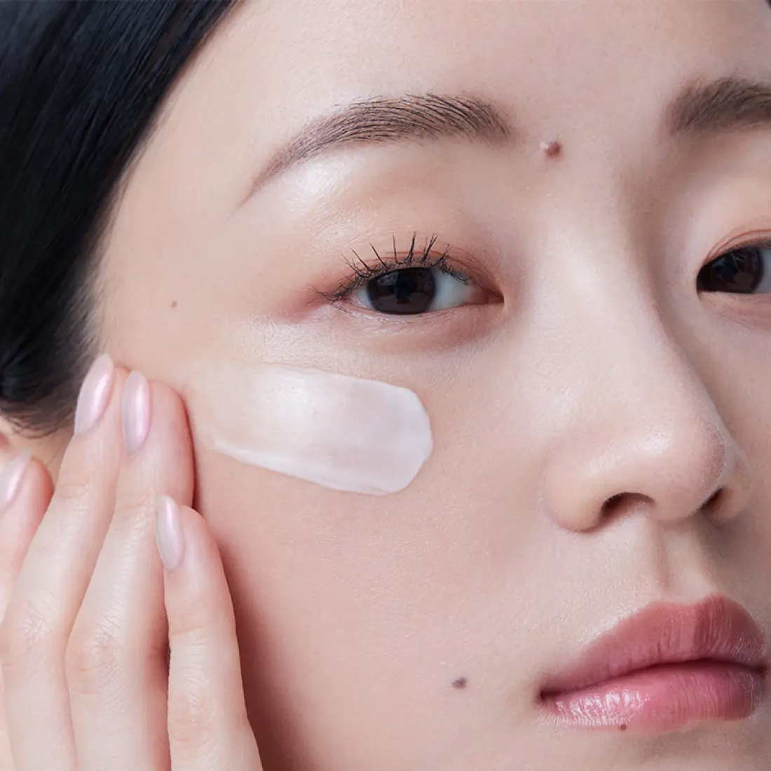 Woman applying HERA Rejuvanate Ampoule Cream 50ml on cheek for skincare