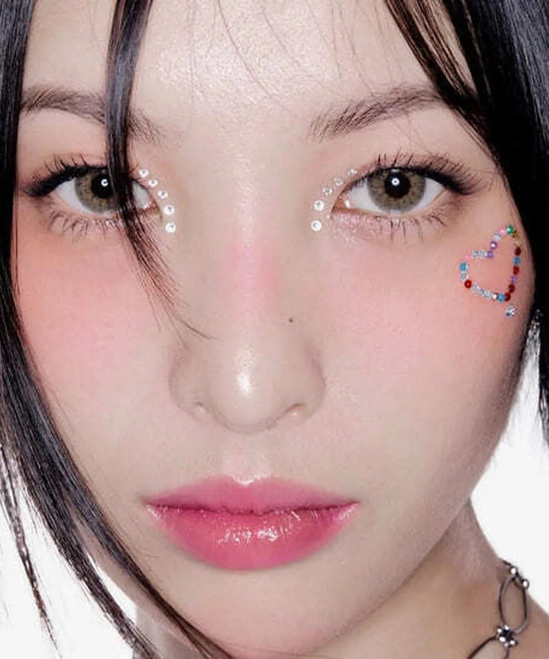 Close-up of model with decorative face gems and soft makeup highlighting HERA Sensual Fiting Glow Tint 5g lip tint.
