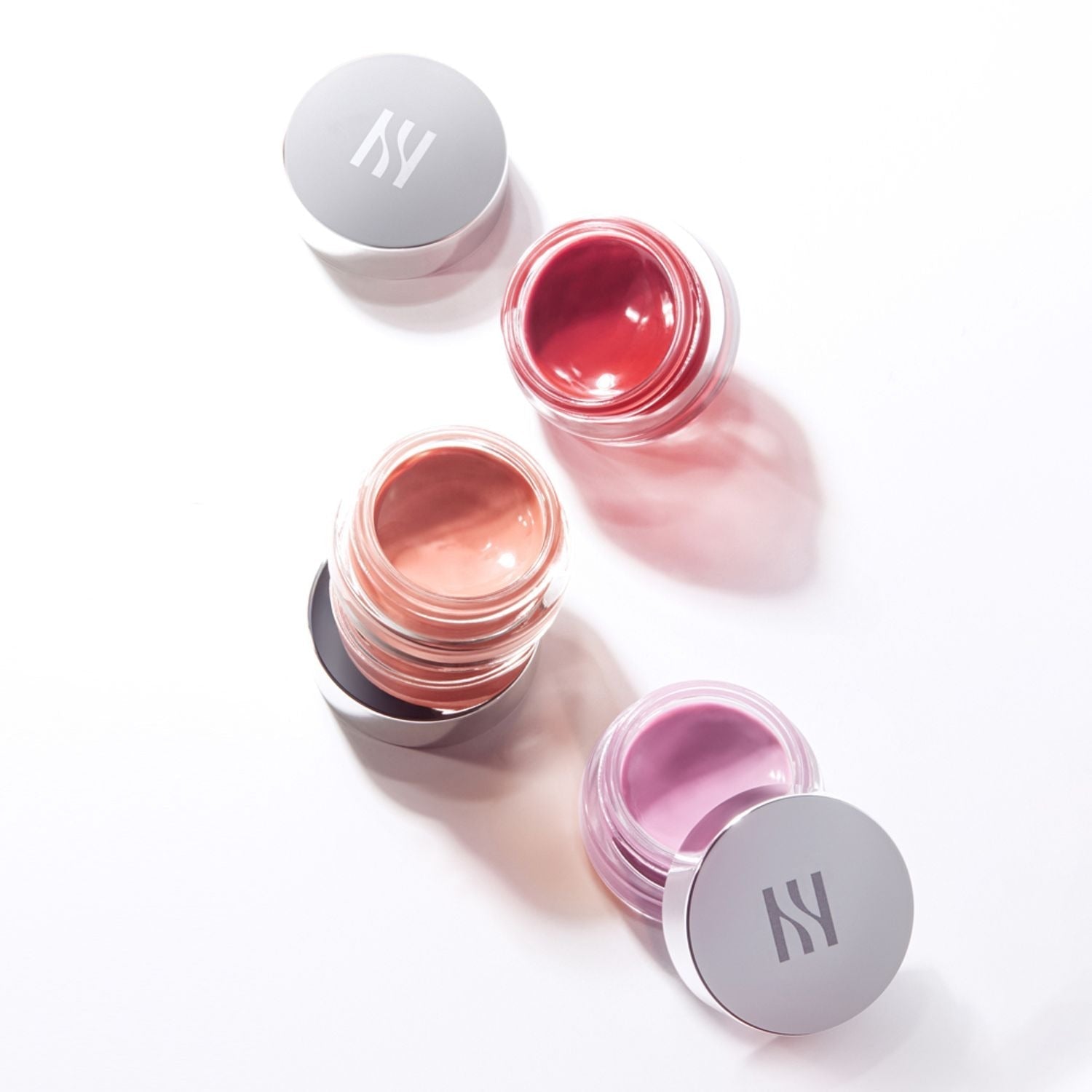 Three open jars of HERA Sensual Lip & Cheek 7g in different shades on a white background.