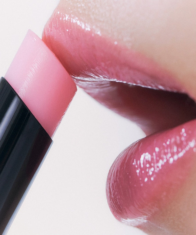 Close-up of lips applying HERA Sensual Nude Balm 3.5g for a natural look.