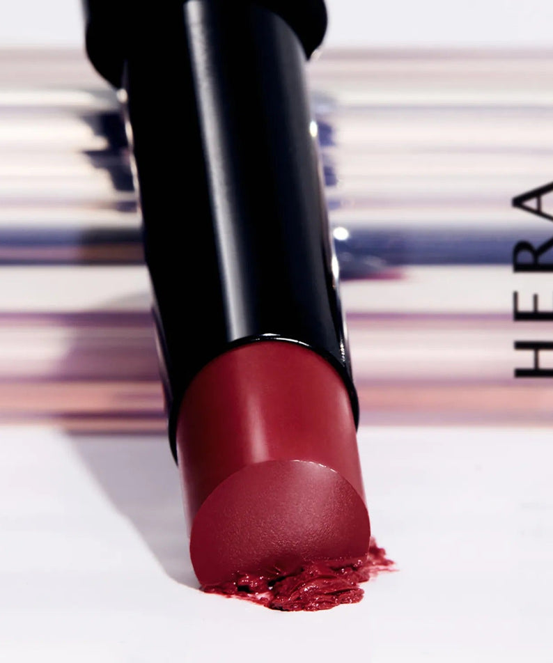 HERA Sensual Tinted Shine Stick 3.5g lipstick close-up with smudged tip against elegant background for beauty products.