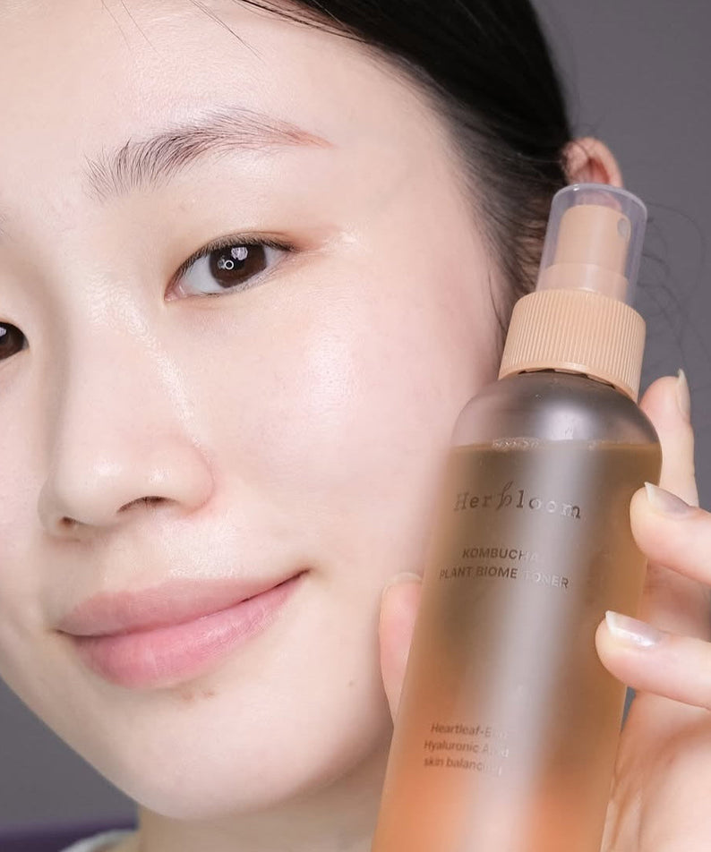 HERBLOOM Kombucha Plant Biome Toner 150g bottle held by person with clear skin, highlighting natural skincare benefits.