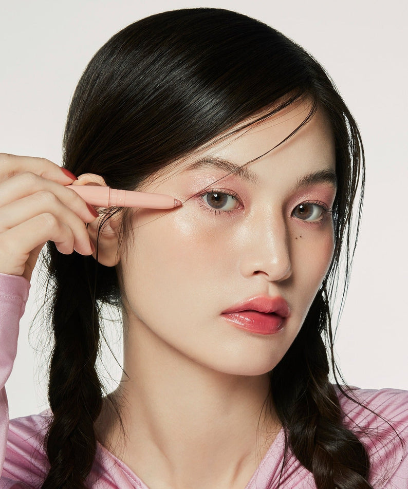 Model applying HINCE Depth Dual Color Stick on eyelids, showcasing vibrant makeup look.