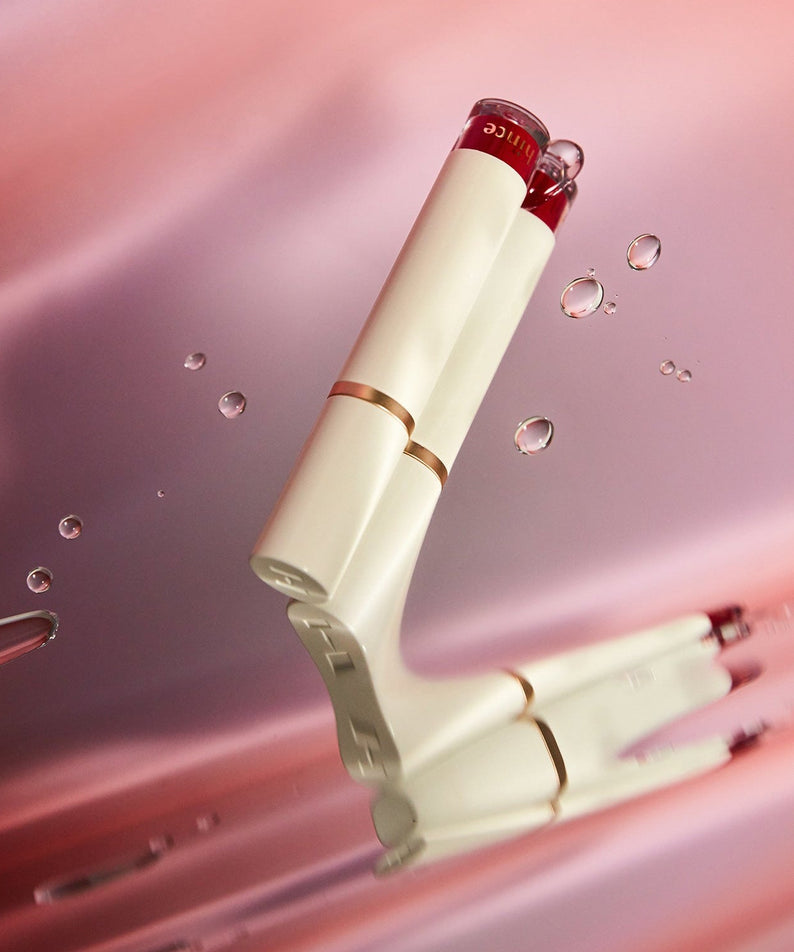 HINCE Mood Enhancer Water Liquid Glow product on a pink background with water droplets.