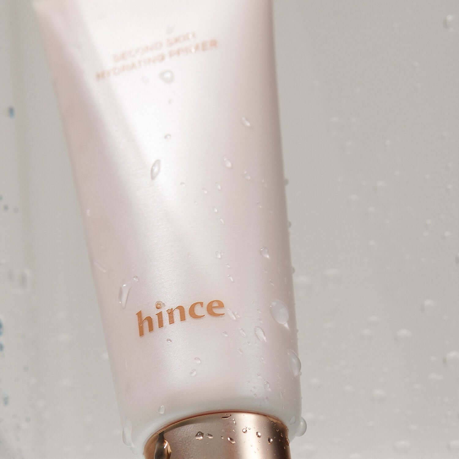 HINCE Second Skin Hydrating Primer with water droplets on the packaging, showcasing sleek and radiant design for flawless skin application.