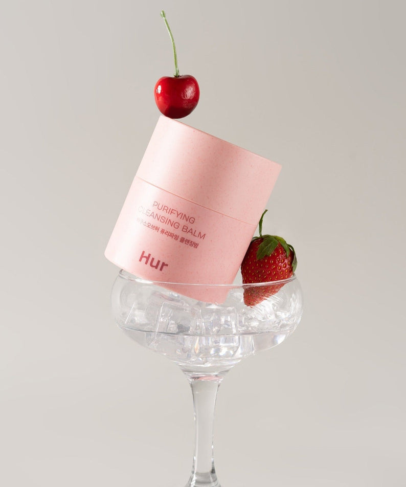 HOUSE OF HUR Purifying Cleansing Balm displayed with cherry and strawberry in a glass.