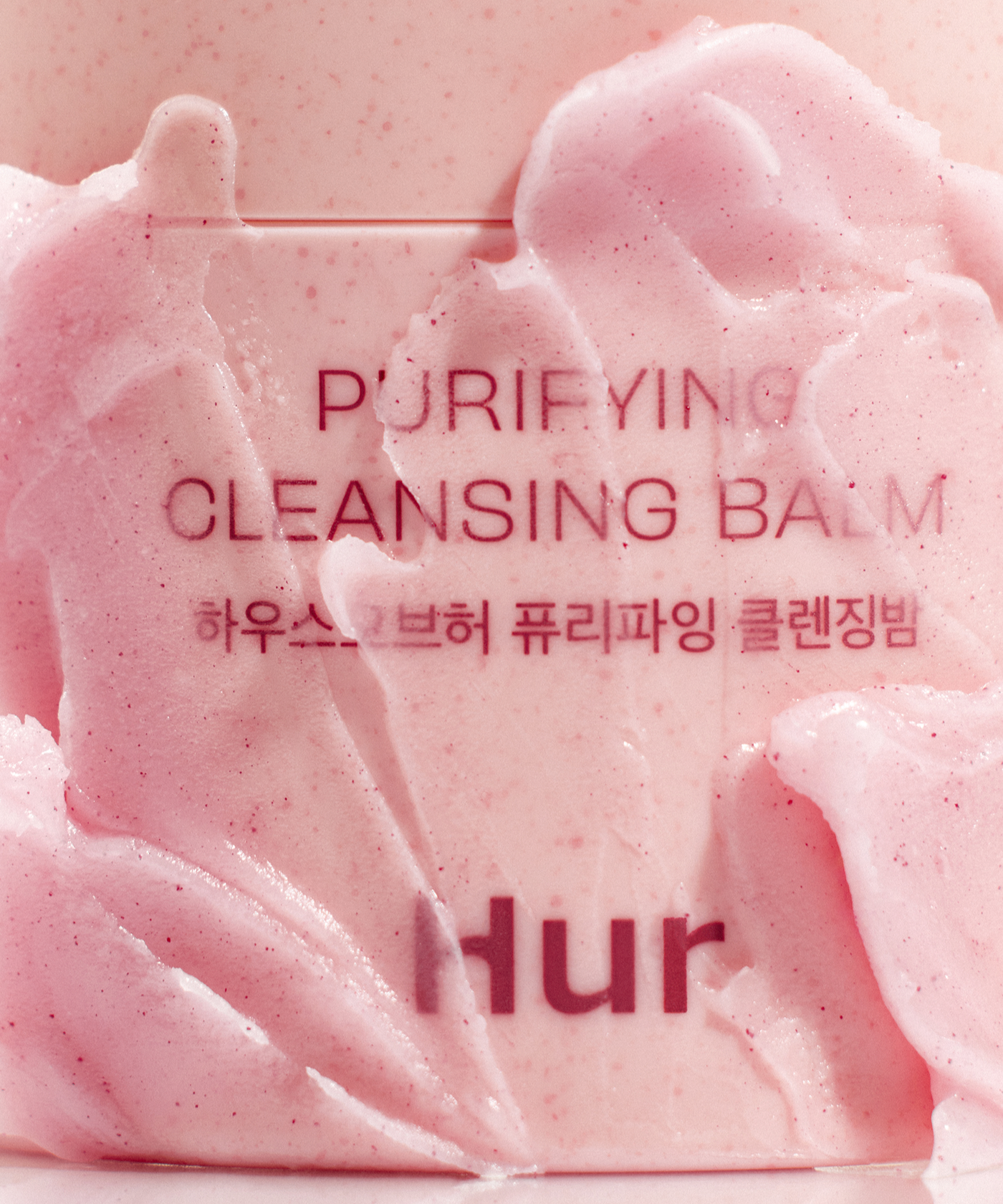 Close-up of HOUSE OF HUR Purifying Cleansing Balm with textured pink balm on the container surface.