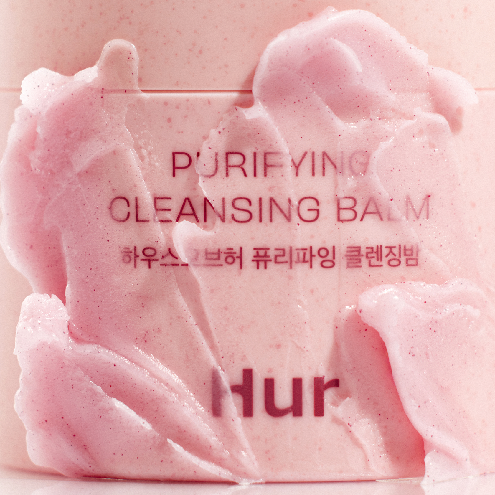 Close-up of HOUSE OF HUR Purifying Cleansing Balm with textured pink balm on the container surface.