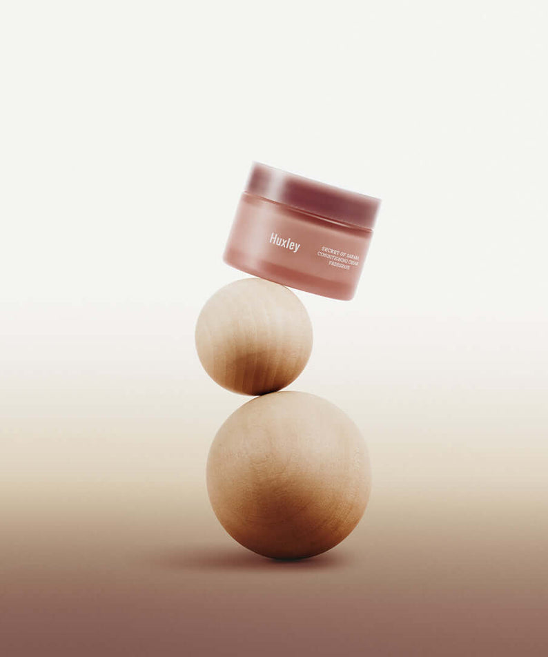 HUXLEY Conditioning Cream Preshape jar artfully balanced on wooden spheres for skincare promotion.