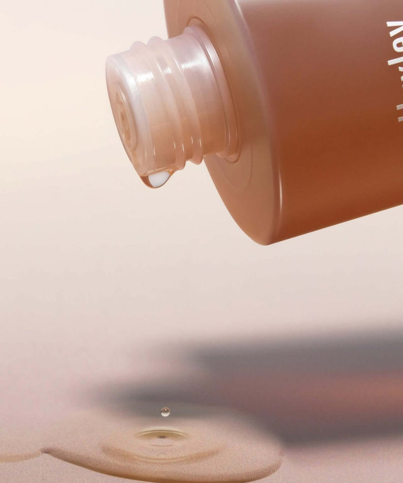 HUXLEY Conditioning Essence Toner Preshape bottle with liquid pouring, highlighting the skincare product's hydrating properties.