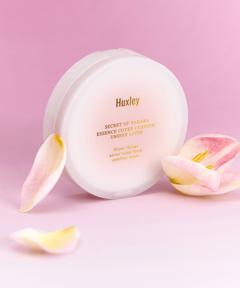 HUXLEY Essence Cover Cushion Unseen Layer displayed with floral petals on a pink background for skincare and beauty care.