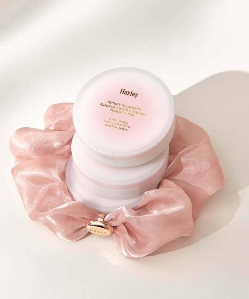 HUXLEY Essence Cover Cushion Unseen Layer displayed with elegant pink silk fabric backdrop.