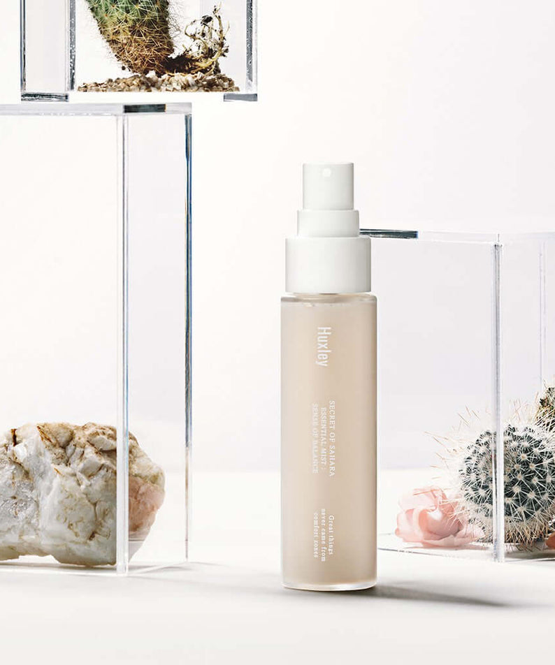 HUXLEY Essential Mist Sense Of Balance hydrating mist bottle amid cacti background.