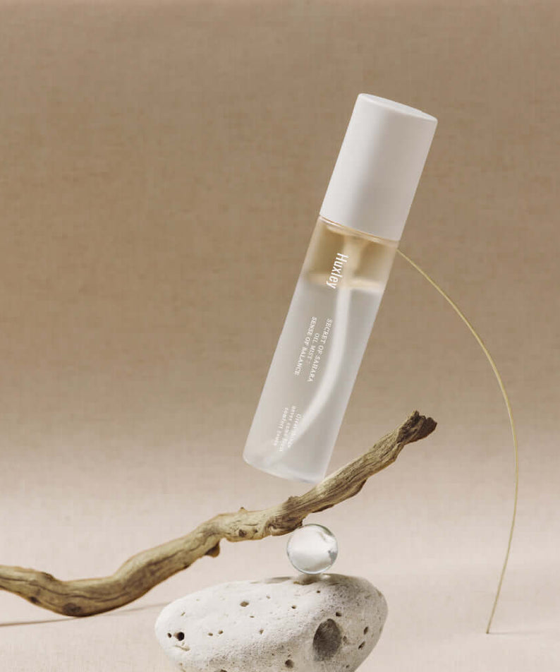 HUXLEY Oil Mist Sense Of Balance product image with elegant minimalistic background, showcasing the sleek bottle design on a beige surface.