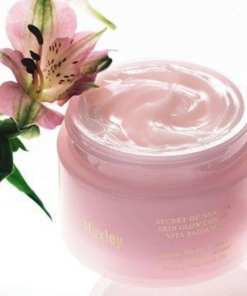 Open jar of HUXLEY Skin Glow Cream Vita Radiance with floral design, showcasing smooth texture for revitalized skin care