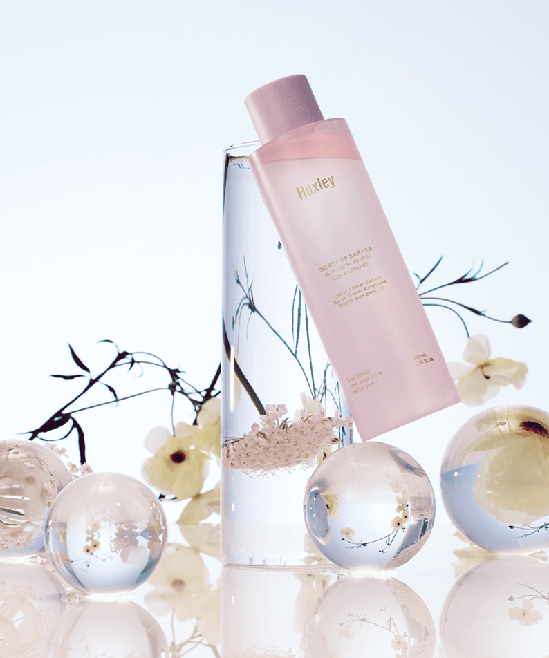 HUXLEY Skin Glow Toner Vita Radiance with decorative floral elements and glass spheres, enhancing beauty and radiance.